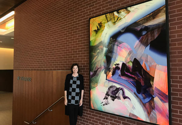 Graceland Communications Director and Art Curator, Jeanne Davis showcases the bold Loree piece now hanging in Shaw Center outside the JR Theatre.