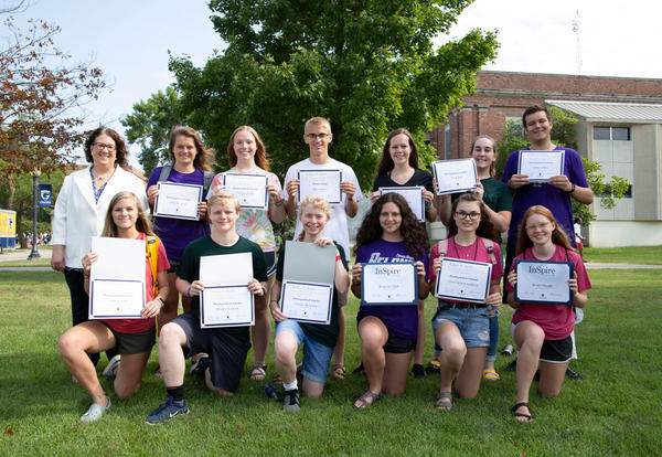 Scholarship winners showing off their certificates while posing outside Closson Center with Graceland President Patricia H. Draves