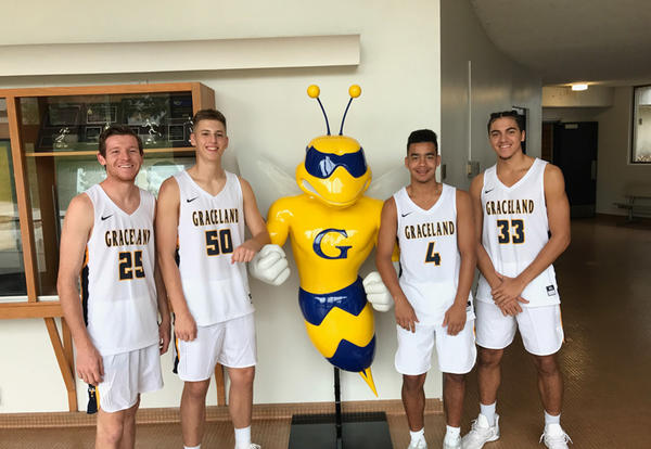 Men's basketball team members stand with new Sting Yellowjacket mascot statue