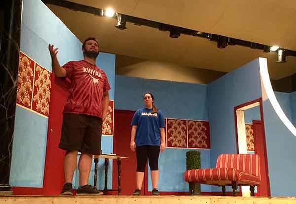 Male and female theatre students rehearsing on a dressed stage