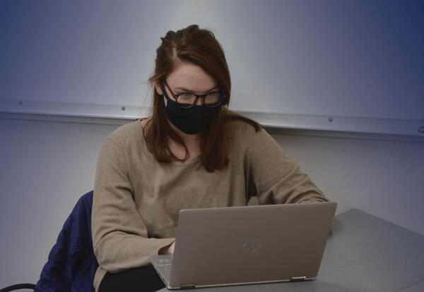 Student in mask working on laptop