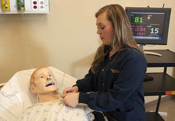 Female nursing student in lab practicing on a patient simulation mannequin