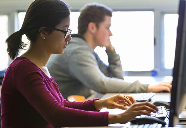 Female and male student working at desktops