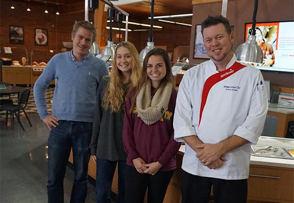Professor Dan Platt, two female students and Sodexo chef pose in the Commons eating hall
