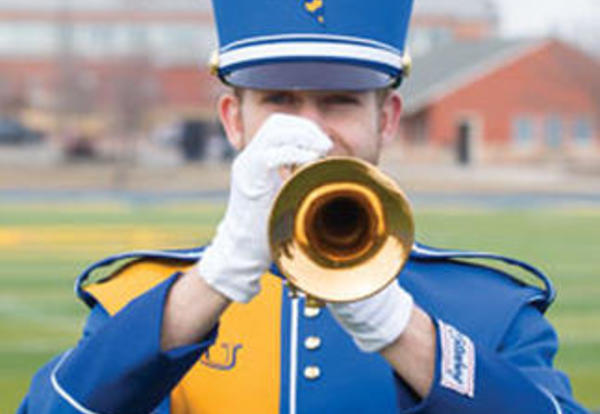 Male marching band student in uniform playing his horn