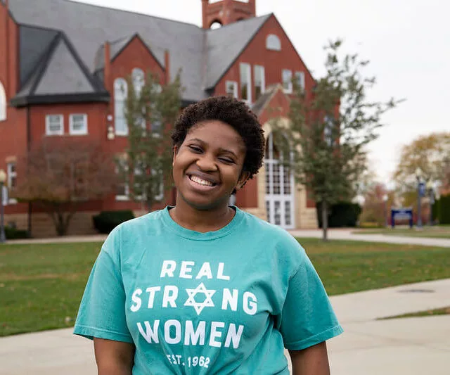 Student smiles in front of Higdon building