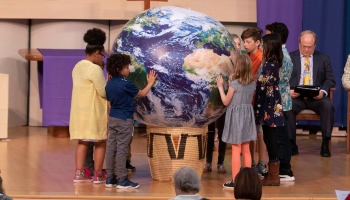 Children surrounding globe sculpture