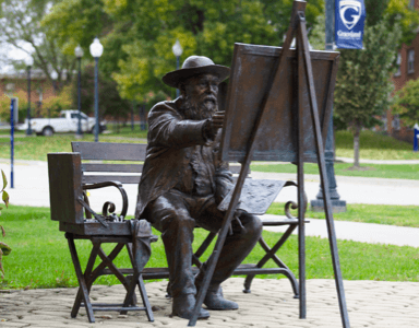 Statue of a painter outside of the Helene building