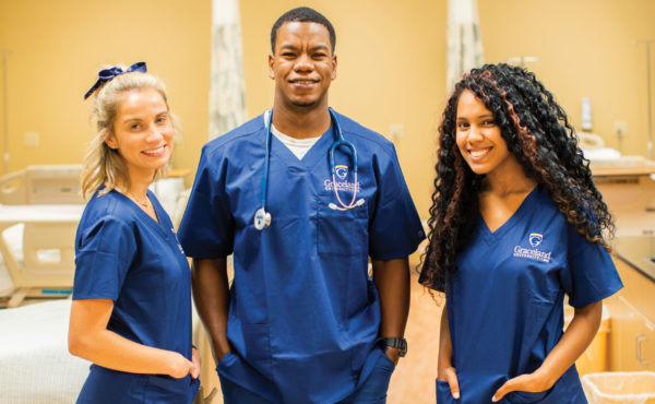 smiling nursing students pose in hospital classroom