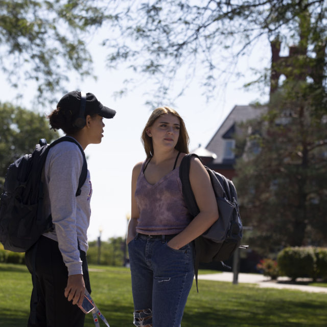 students stand and talk on campus