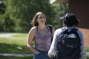 closeup of smiling students stand and talk on campus