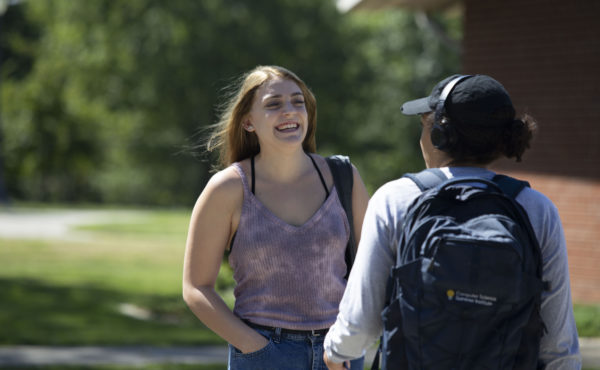 closeup of smiling students stand and talk on campus