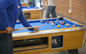 closeup of student playing pool in game room