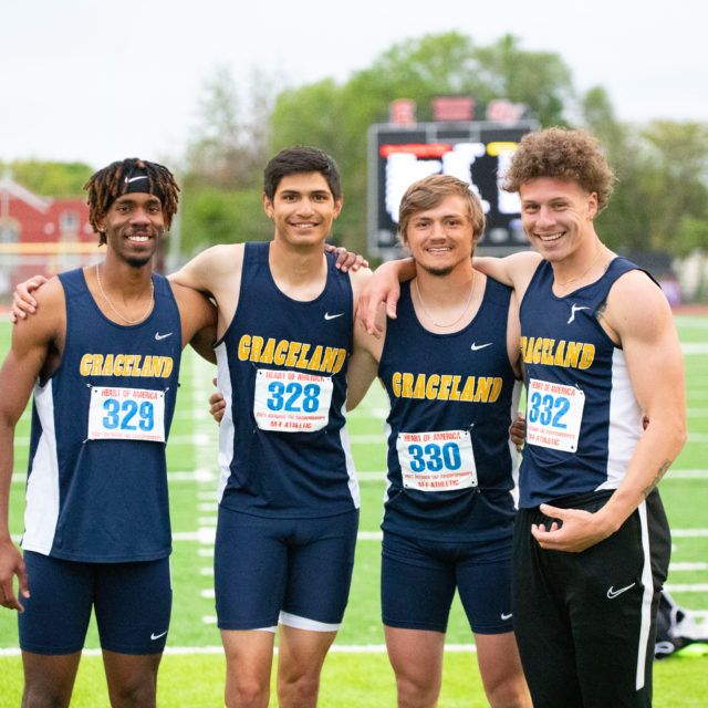 smiling men's track and field student athletes pose together at competition