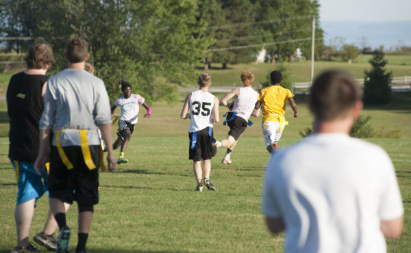 male students playing intramural flag football on practice soccer field