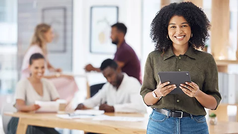 Young professional woman taking notes on a tablet during a business meeting.