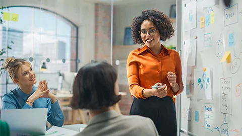 African American woman leading a discussion in front of a white board.