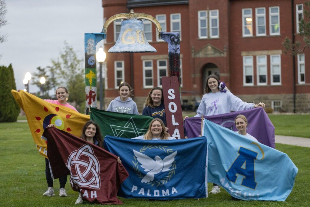 female students on a university campus in front of a bell